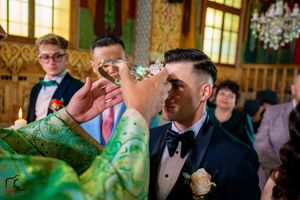 Orthodox wedding ceremony features traditional crown ritual with formal attire and decorative interior.