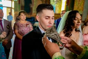 Orthodox wedding ceremony features traditional crown blessing with formal attire.