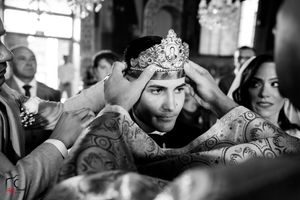 Black and white photo captures intimate moment during Orthodox wedding crown ceremony.
