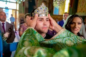 Ornate crown being placed during traditional wedding ceremony with green and gold decorative elements.