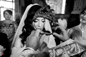 Black and white photo of wedding ceremony showing crown placement and traditional elements.
