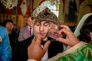 Wedding ceremony detail shot focusing on ornate crown and decorative green fabric.