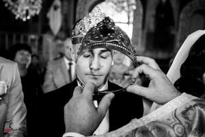 Artistic wedding photo showing crown ceremony with traditional decorative elements.