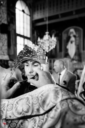 Black and white photograph showing a ceremonial moment with decorative elements and stained glass windows.