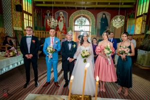 Full view of wedding party gathered in a traditional church with ornate architectural details.