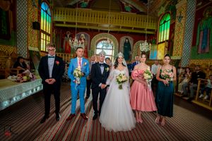 Panoramic view of wedding ceremony participants lined up in a decorated church interior.