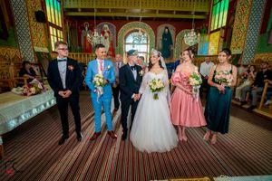 Wedding party gathered in a grand hall with decorative gold trim and chandeliers.