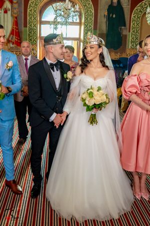 Wedding celebration in a luxurious room with ornate wallpaper and striped carpeting.