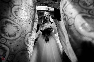 Black and white wedding ceremony photo with ornate decorative patterns in the background.
