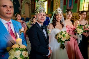 Wedding party gathered in an ornate venue with pink bridesmaid dresses and floral decorations.