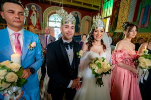 Wedding ceremony participants in formal attire standing in a decorated venue with pink and blue accents.