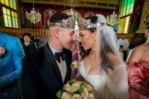 Wedding ceremony in an ornate Orthodox church with crystal chandeliers and decorative ceiling.