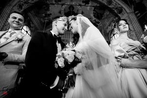 Dramatic black and white wedding photo showing couple during Orthodox ceremony.