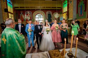 Wide view of Orthodox church interior during wedding ceremony with green-robed clergy.