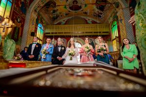 Panoramic view of Orthodox church wedding with ornate ceiling and stained glass windows.