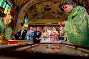 Orthodox wedding ceremony with green-robed clergy and elaborate church architecture.