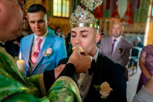 Orthodox wedding ceremony with traditional crowning ritual and decorated church interior.