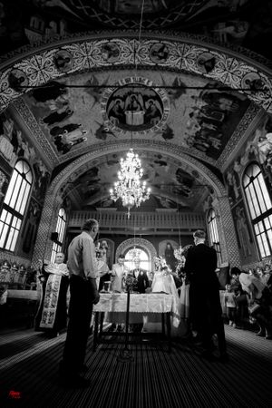 Black and white silhouettes of wedding guests in a grand ballroom with dramatic lighting.