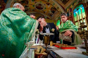 Priests in emerald green robes perform a traditional Orthodox ceremony at an ornate altar.