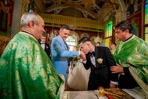 Religious ceremony taking place inside an ornate church with stained glass windows and decorated ceiling.