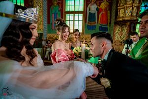 Traditional Orthodox wedding ceremony taking place in a beautifully decorated church with painted walls.