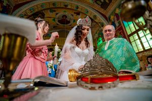 Wedding ceremony participants gather around an ornate altar during an Orthodox service.