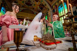 Orthodox wedding ceremony in an ornate church with green and gold decor and stained glass windows.