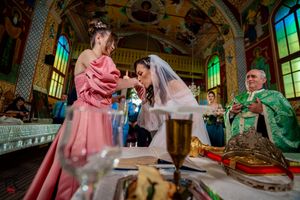 Traditional Orthodox wedding ceremony with participants gathered around ceremonial items at the altar.