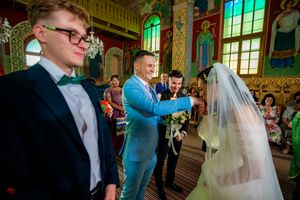 Traditional religious ceremony taking place in a beautifully decorated orthodox church interior.