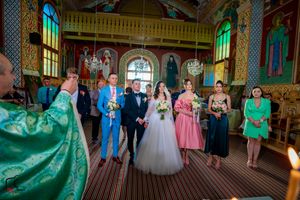 Ceremonial procession in an ornate orthodox church with decorative walls and arched windows.