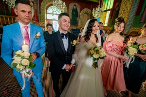 Orthodox wedding service with attendees in formal attire inside an ornate church setting.