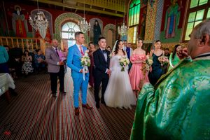 Wedding ceremony in an ornate church with colorful stained glass windows and decorative murals.