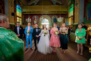 Formal wedding ceremony in a historic orthodox church with elaborate wall decorations.