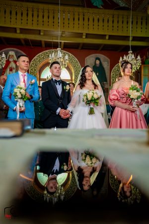 Wedding ceremony reflection shot showing ornate church interior and decorative details.