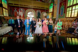 Wedding party photo with perfect mirror reflection on church floor showing colorful interior.