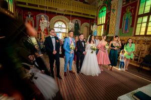 Wedding celebration in a beautifully decorated orthodox church with painted walls and arched windows.