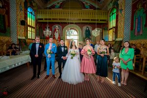 Wedding party lined up in traditional church with elaborate wall paintings and stained glass windows.