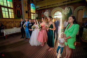Wedding celebration in decorated orthodox church with painted walls and dramatic window lighting.