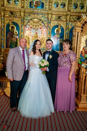 Wedding party group photo in front of an elaborate golden iconostasis with striped carpet.