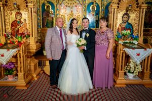 Wedding party poses together against ornate gold church altar with religious icons.