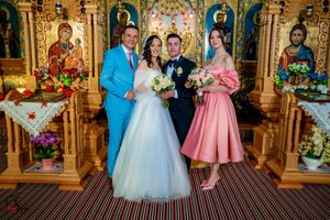Wedding party members in formal attire pose in front of an ornate gold church altar.