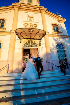 Elegant church facade with white columns and arched windows against vibrant blue sky.