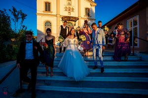 Wedding party and guests assembled outside traditional church at dusk.