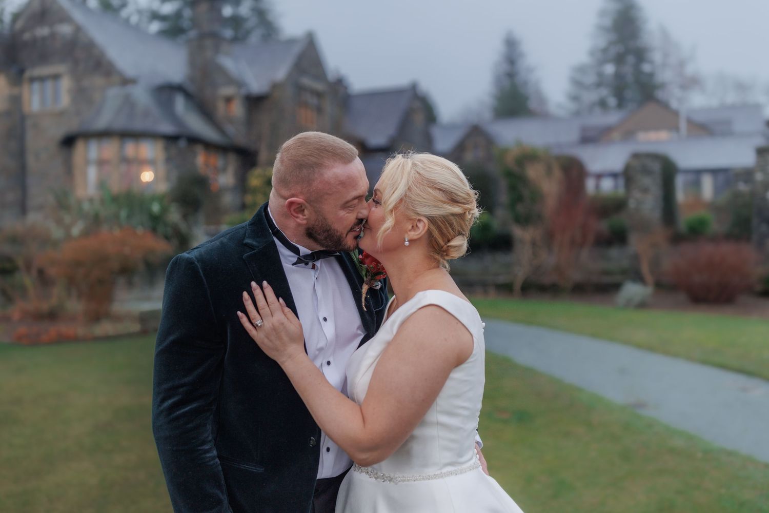 A romantic wedding moment at a stately venue with manicured grounds.
