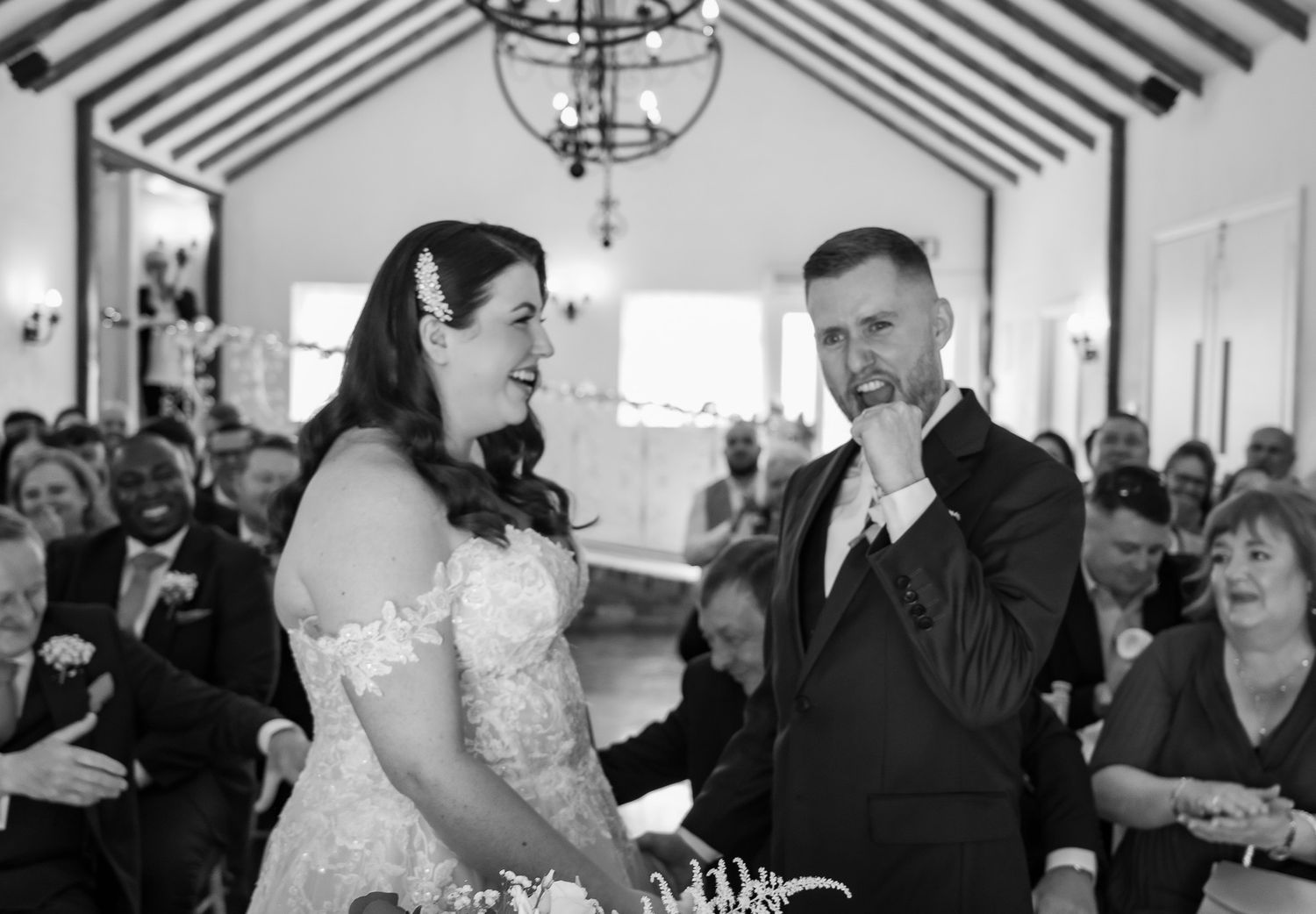 A joyful moment between a bride and groom sharing laughter during their wedding ceremony in a chapel.