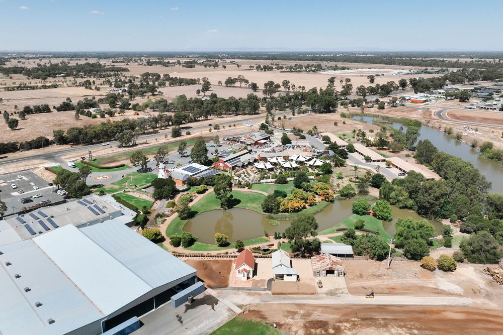 Aerial panoramic view of a rural town with roads, buildings, and farmland stretching into the distance on a clear day.