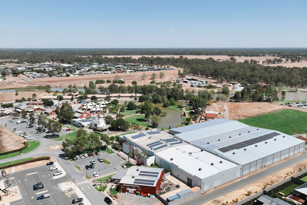 Aerial view of industrial buildings and commercial warehouses surrounded by parking lots and green fields.