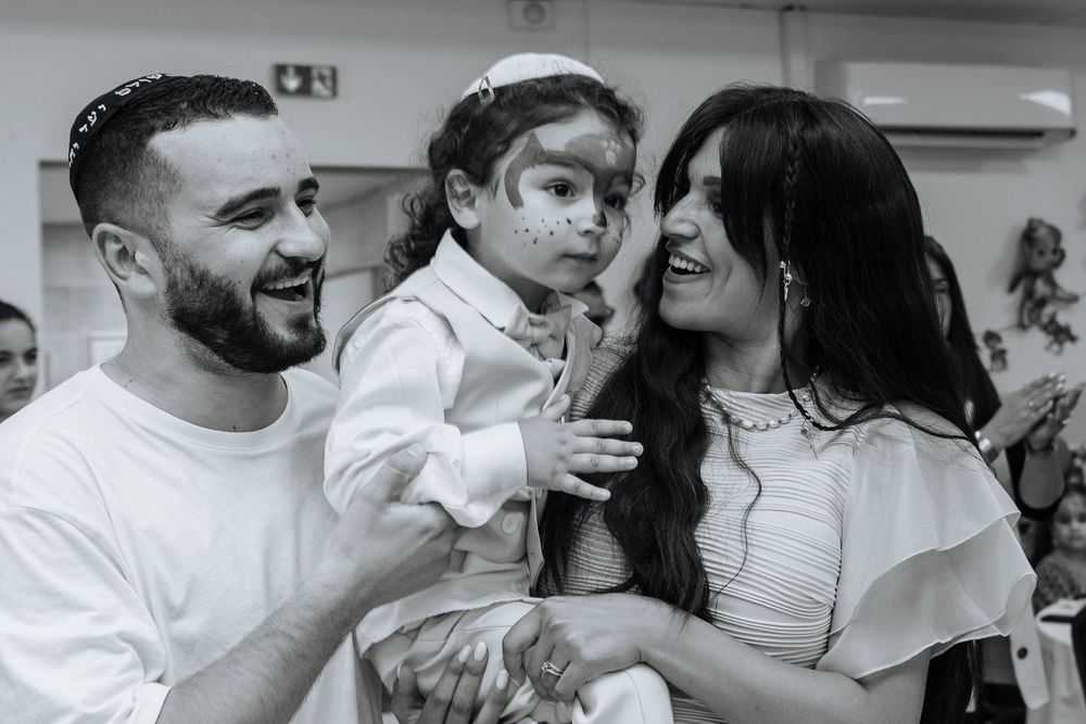 A joyful family moment in black and white as they celebrate with white powder on their faces during a special occasion.