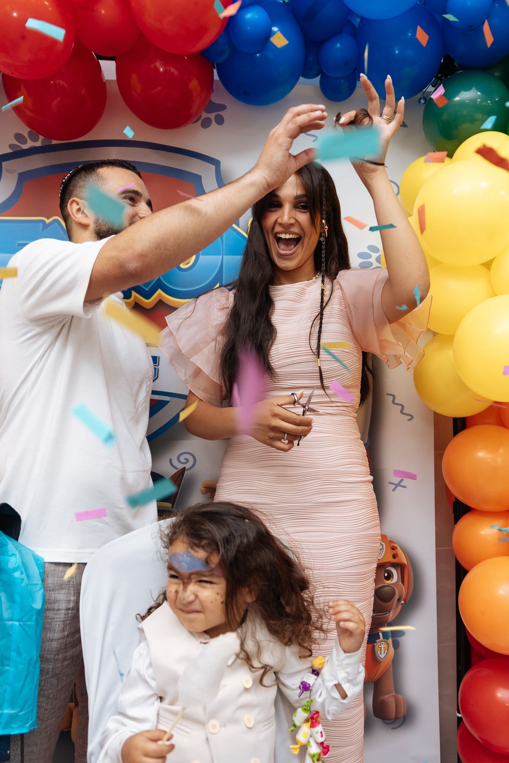 People celebrating at a party with colorful balloons and confetti in a festive atmosphere.