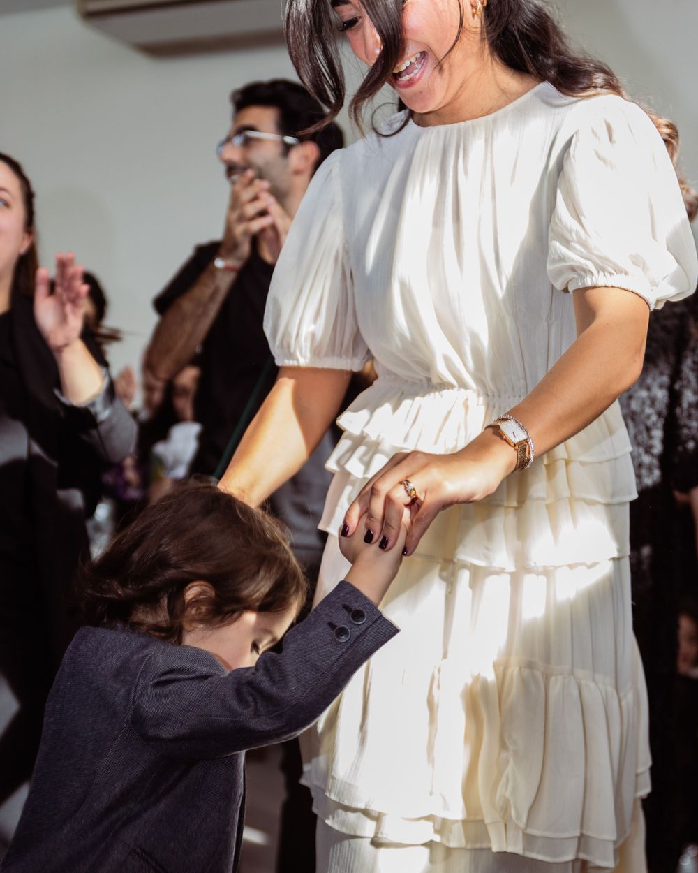 A tender moment at a party as a child holds onto his mother wearing a white dress.